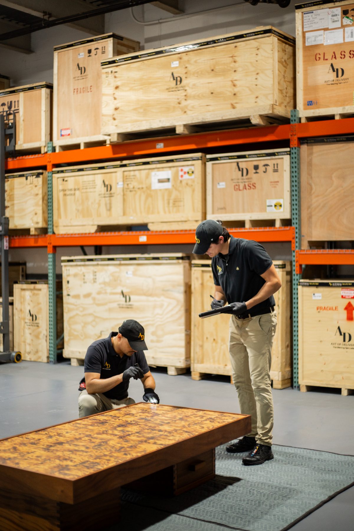 Specialists condition-checking a table among racked crates