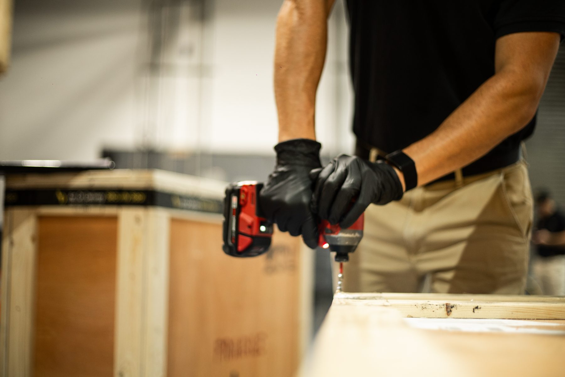 Gloved hands driving screws into a custom crate panel